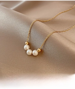 Detailed macro view of three pearls and gold beads on a delicate chain over silk