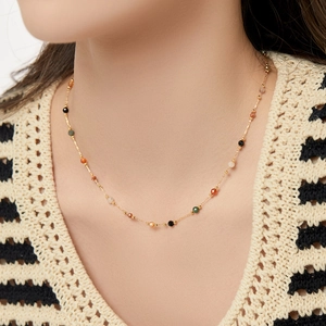 Minimalist gold necklace with colorful natural stone beads on a model's neck