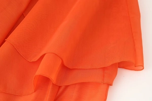 Detail of vibrant orange tiered chiffon fabric showing delicate texture and ruffled edges