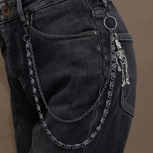 Detail of punk double-layer gunmetal jeans chain with a skull pendant on black denim