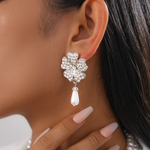 Close-up of sparkling rhinestone flower earrings with elegant teardrop pearl pendants