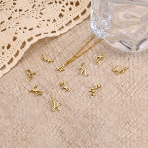 Golden heart-accented initial pendants displayed on beige linen with lace decor