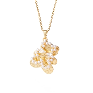 Golden bear pendant necklace with pearl trim and rhinestone bowtie on white background