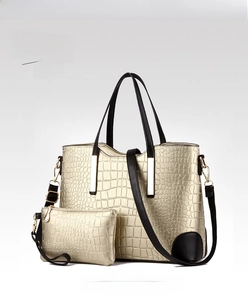 Macro detail of golden crocodile pattern tote bag with metal trim and black strap