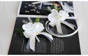 Detail view of white artificial orchid boutonniere and wrist corsage set for weddings