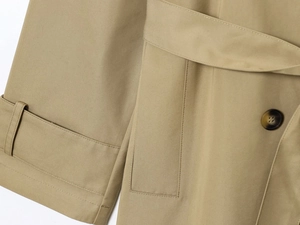 Dettaglio del trench kaki che mostra la trama del tessuto twill e le cuciture precise