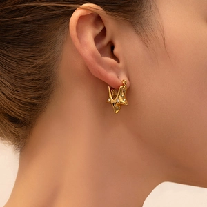 Close-up of vintage gold fan-shaped star earrings with white zircon on earlobe