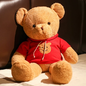 Soft brown teddy bear plush toy wearing a cute red hoodie sitting on a cozy white bed