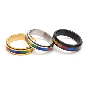 Dettaglio di tre anelli rotanti con strisce arcobaleno in oro, argento e acciaio nero