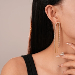 Close-up of elegant gold tassel earrings with zircon crystals on a female model