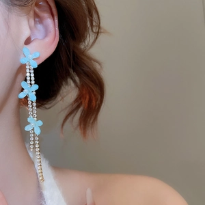 Detail of light blue resin flower earrings with shimmering rhinestone tassel chains