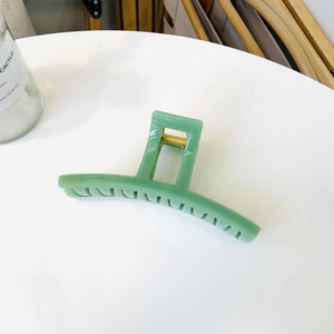 Detailed view of an avocado green hair claw clip with a strong golden metal spring