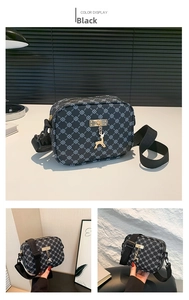 Detail of black crossbody bag with white flower pattern, gold deer charm and wide strap