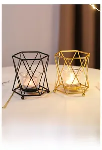 Detail of geometric iron candle holders in black and gold finishes with glass cups