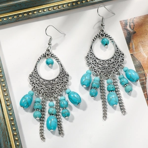 Detail of bohemian silver tassel earrings with sky blue turquoise beads on white background