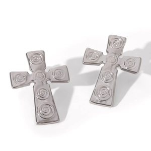 Macro shot of silver stainless steel cross earrings with intricate spiral texture detail