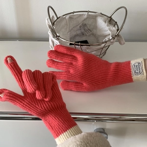 Detail of pink and beige knitted gloves with touchscreen finger openings and ribbed cuffs