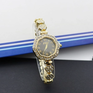 Gros plan d'une montre bracelet dorée à fleurs avec cadran octogonal noir et cristaux brillants