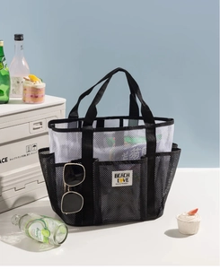 Detail of a black and white mesh beach bag featuring multiple functional side pockets