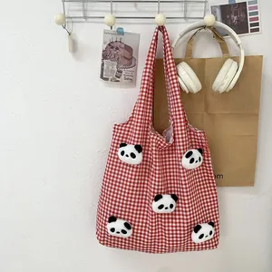 Detail of red and white checkered canvas tote bag with 3D plush panda dolls decoration