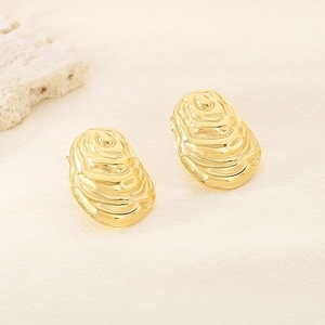Macro detail of gold oval earrings featuring artistic water ripple texture and 3D relief