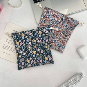 Flat lay of floral drawstring pouches for skincare and accessories on a white desk