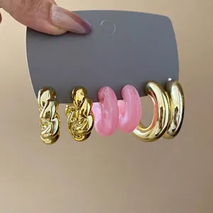 Six-piece set of twisted gold and pink acrylic hoop earrings with stylish textured design