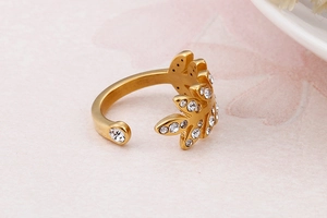 Gros plan d'une bague feuille dorée sertie de zircons sur fond floral doux