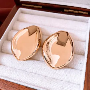 Boucles d'oreilles feuille d'or au fini métal liquide sur fond de tissu blanc