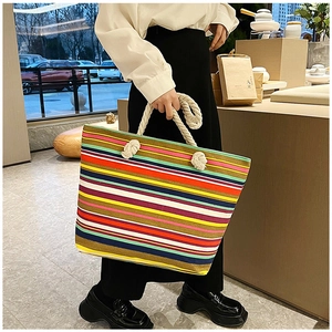 Close-up of colorful striped canvas tote bag with thick beige rope handles shown in-store