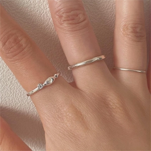 Close-up of three-piece silver ring set including a heart-moon design and thin bands