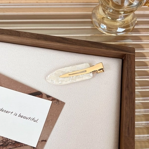 Detail shot of vintage style duckbill hair clip with textured pearl finish on wooden tray