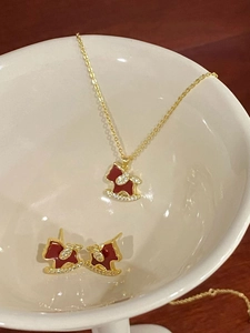 Detailed view of 18K gold plated rocking horse necklace and earrings set with red enamel