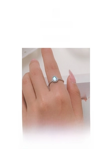 Detail of a pear-shaped moonstone ring with pavé diamonds on a minimalist silver band