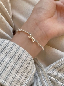 Close-up of a sterling silver bow bracelet featuring unique irregular twisted chain links