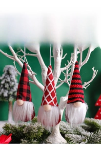 Close-up of three knitted Christmas gnomes with plaid and striped hats hanging on branches