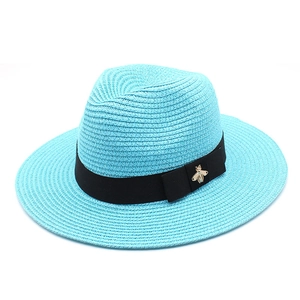 Detailed weave of turquoise Panama hat with black ribbon and gold bee emblem