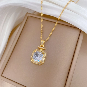 Gros plan d'un collier doré avec pendentif carré en cristal dans un coffret cadeau