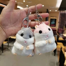Close-up of grey and pink plush hamster keychains held in hand with cute round shapes