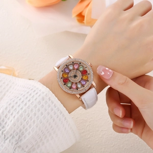 Close-up of women's watch with rose gold case, colorful stones and white leather strap