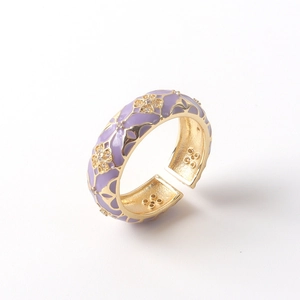 Close-up of 18K gold ring with purple enamel floral pattern and sparkling crystal stones