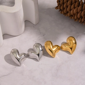 Macro shot of gold and silver heart stud earrings on a grey marble surface decor