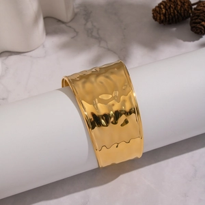 Macro shot of 18K gold hammered finish wide cuff bracelet on elegant white stand