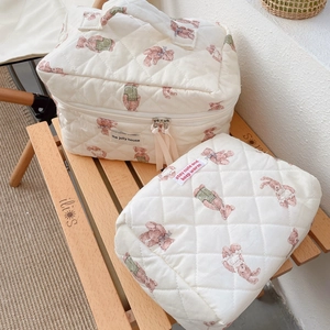 Close-up of quilted cotton bear pattern pouches featuring carry handles and zippers