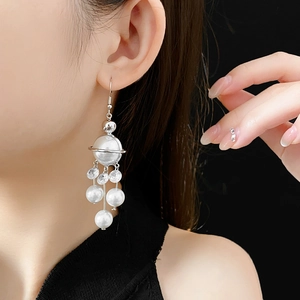 Detail of silver planet fringe earrings with white pearls and sparkling cubic zirconia