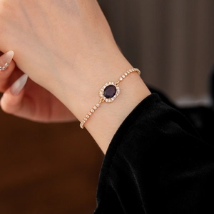 Macro shot of gold bracelet with deep purple oval gem and white zircons on wrist