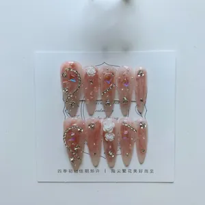 Pink almond press-on nails with 3D white camellia flowers and sparkling rhinestones