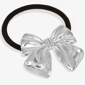Close-up of a silver bow decoration on a black elastic hair tie with polished metal texture