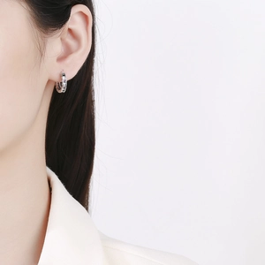 Close-up of a silver zircon hoop earring with purple stones worn by a model