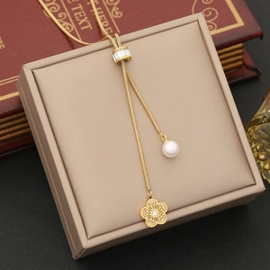 Detail of gold floral pendant and pearl tassel necklace on beige jewelry box display